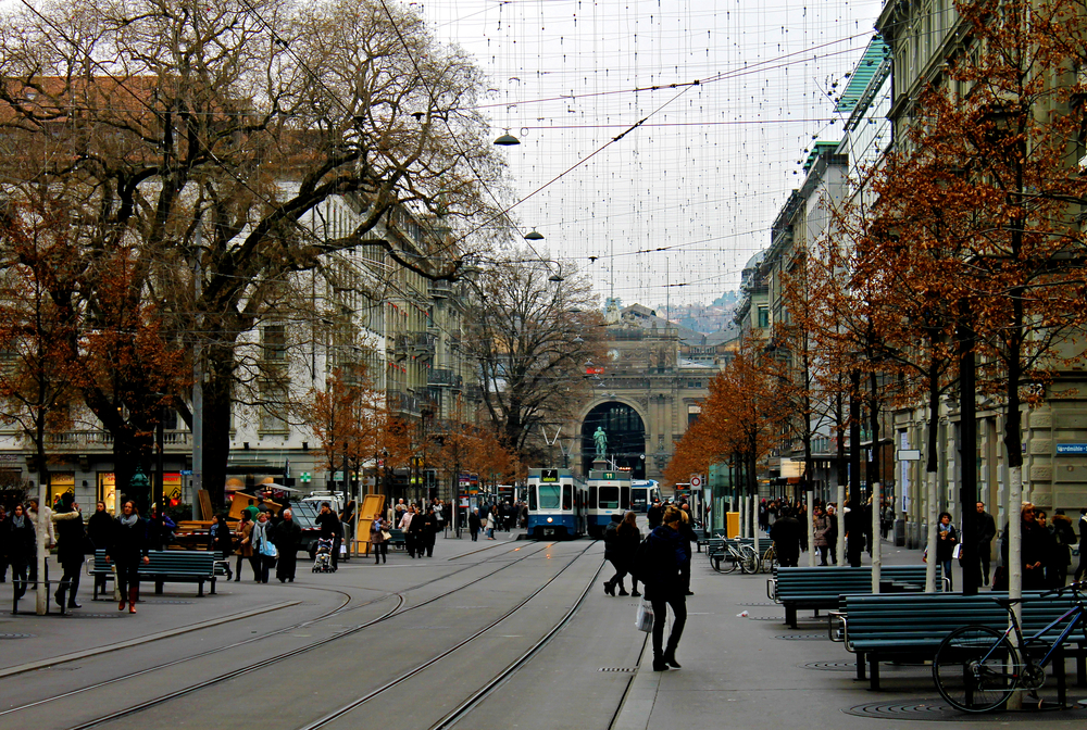 La Bahnhofstrasse à Zurich avec ses rails de tram, ses piétons et la gare centrale au bout de la rue