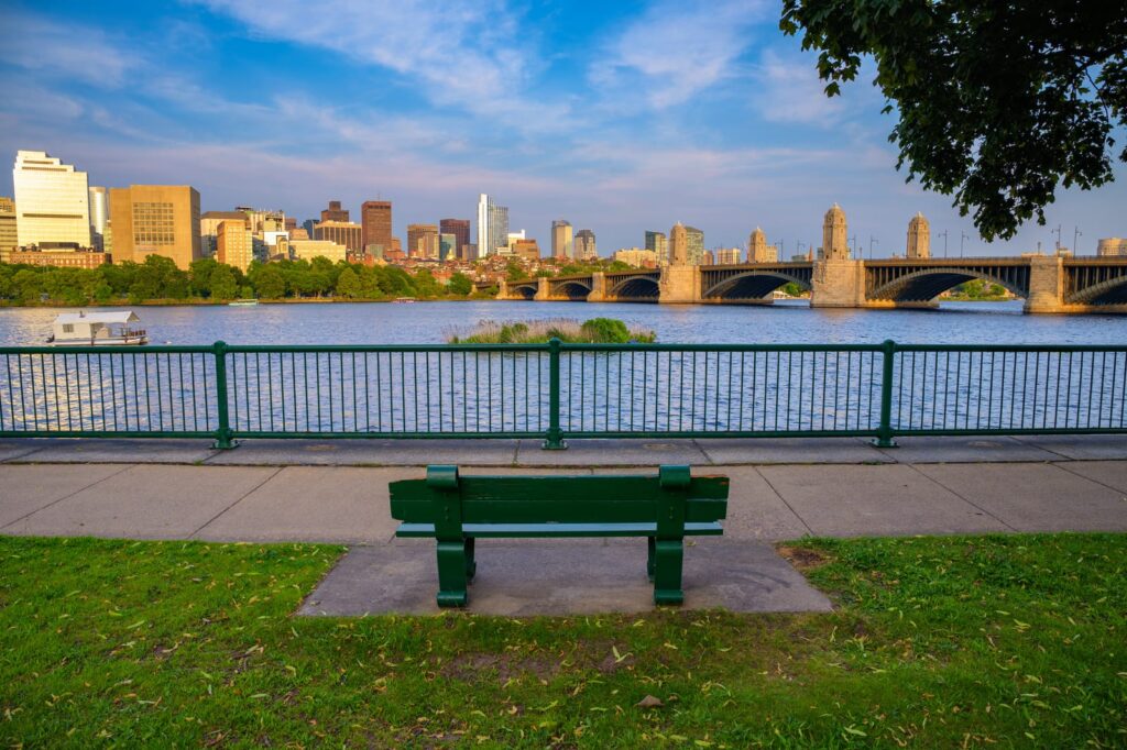 Banc au bord de la Charles River avec la skyline de Boston et un pont au loin