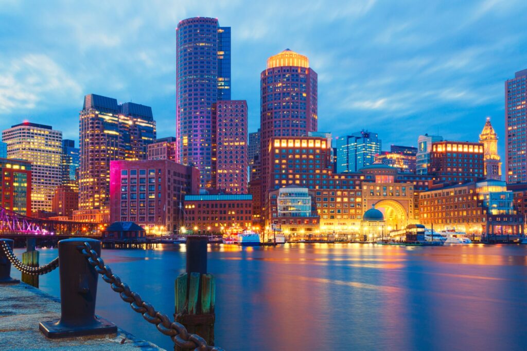 Bâtiments illuminés le long du front de mer de Boston, reflétés dans l’eau au crépuscule