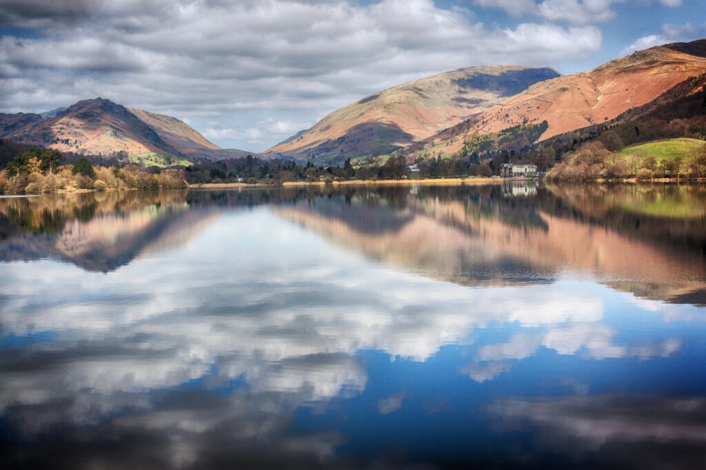 Où dormir dans le Lake District ? Les 5 meilleurs quartiers et hébergements 20 Des collines d’automne et des nuages se reflètent dans l’eau calme de Grasmere