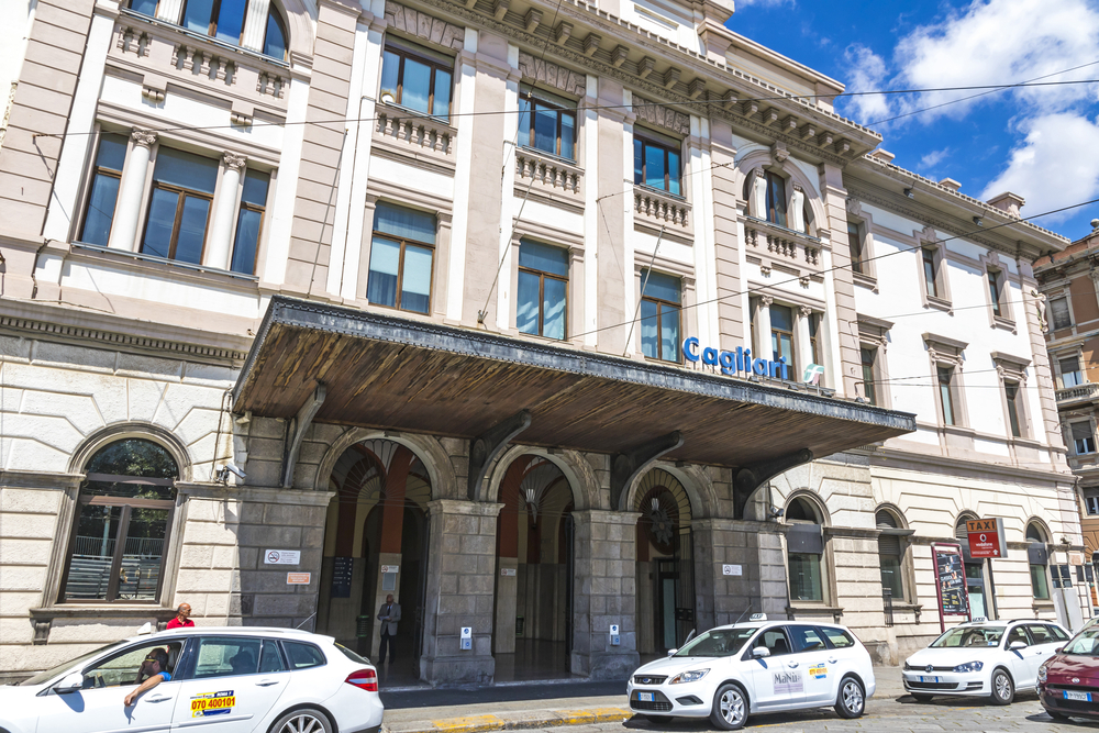 La façade de la gare de Cagliari avec des taxis devant l’entrée