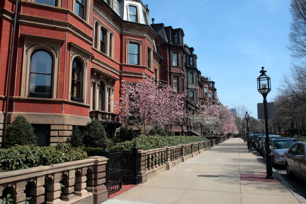 Maisons en briques, arbres en fleurs et grilles le long d’un trottoir à Back Bay