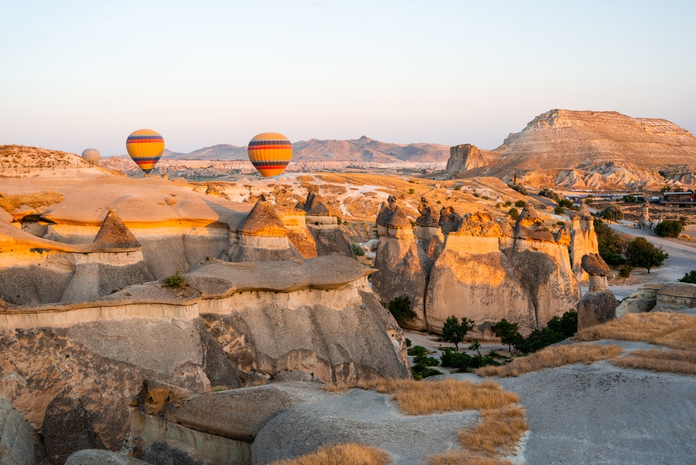 Des montgolfières flottent au-dessus des formations rocheuses de Cappadoce au lever du soleil