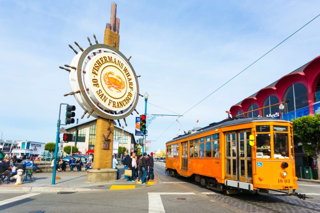 Panneau de Fisherman’s Wharf à côté d’un tramway orange et des bâtiments du front de mer
