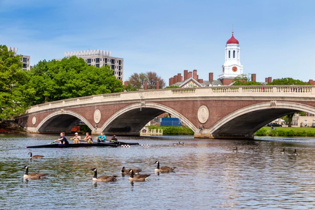 Pont en arche de briques sur la Charles River, avec des arbres et une tour de Cambridge en arrière-plan