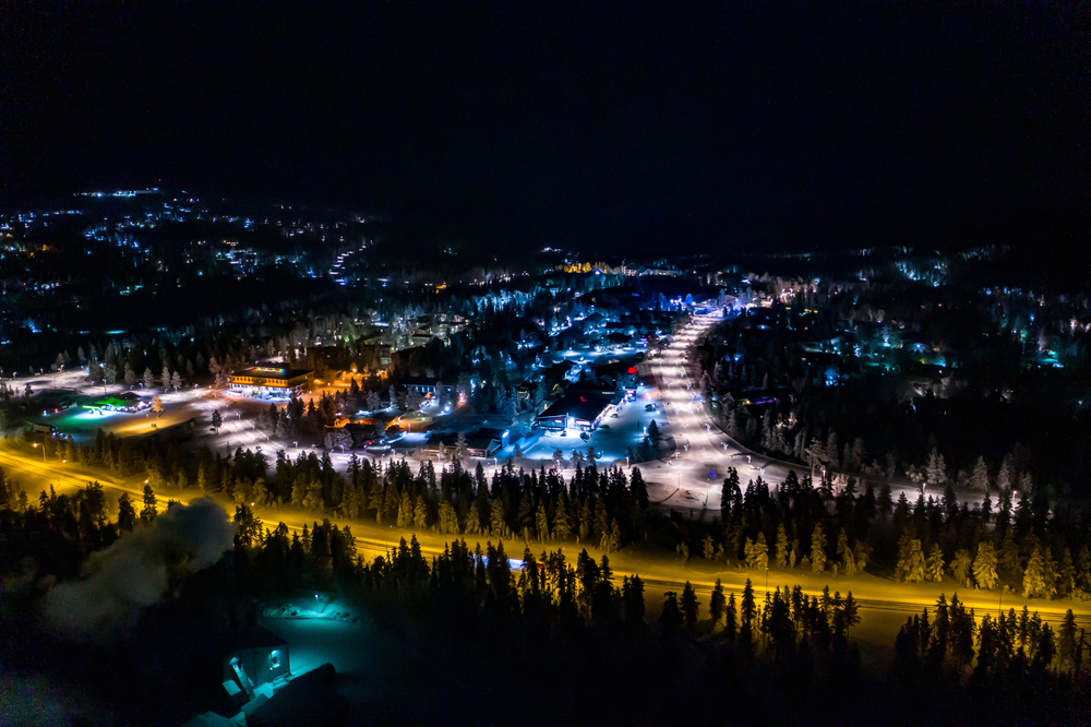 Où dormir en Laponie ? Les 6 meilleures villes et de bons hôtels 12 Vue aérienne de Saariselkä le soir, avec des lumières colorées, en Laponie
