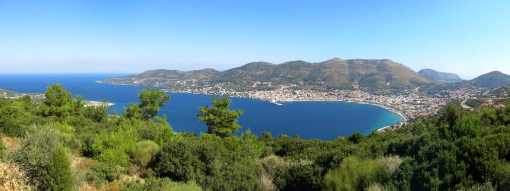 Vue large sur une baie de Samos, avec des pentes boisées et des bâtiments le long de la côte