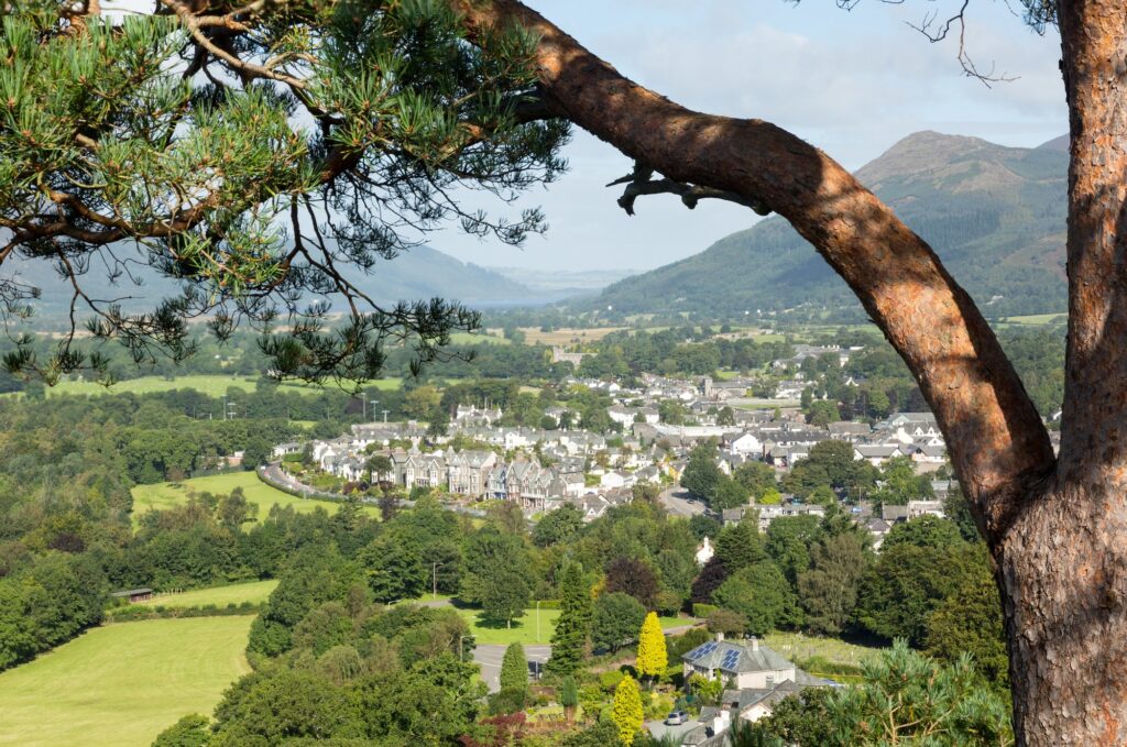 Où dormir dans le Lake District ? Les 5 meilleurs quartiers et hébergements 18 Vue sur Keswick depuis une colline boisée, avec des prés verts et des montagnes au loin